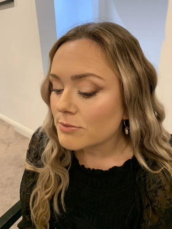 Warm gold eyeshadow with soft lashes and a peach-nude lip, eyes lowered