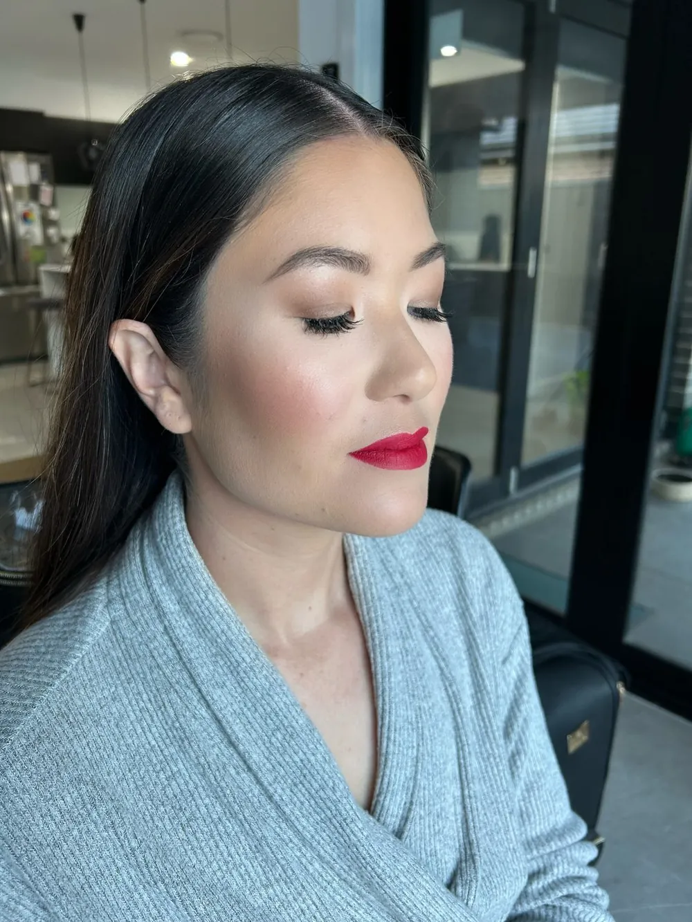 A client wearing Lauren's classic red lip with softly defined, fluttery lashes and luminous skin